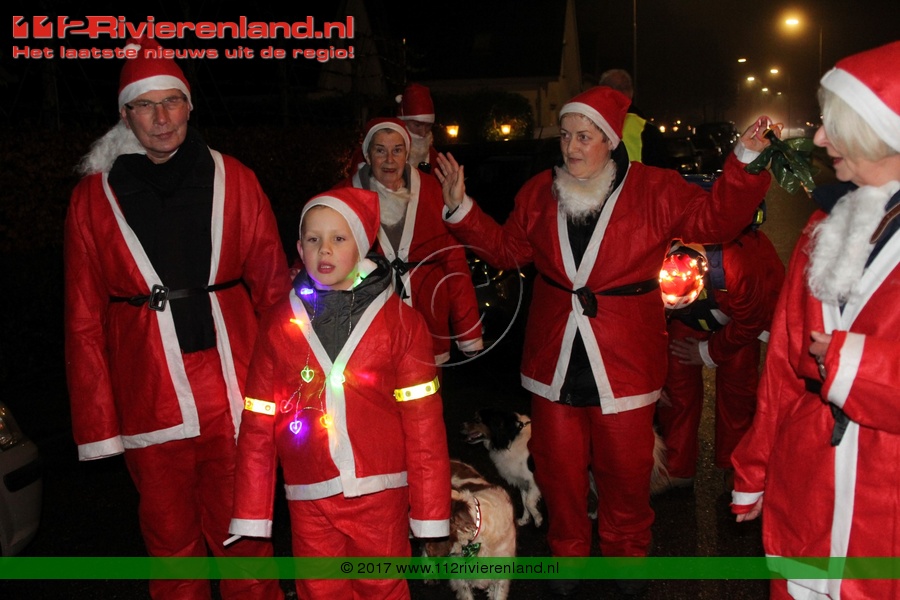 Bonte stoet van kerstmannen en vrouwen trekken door dorp