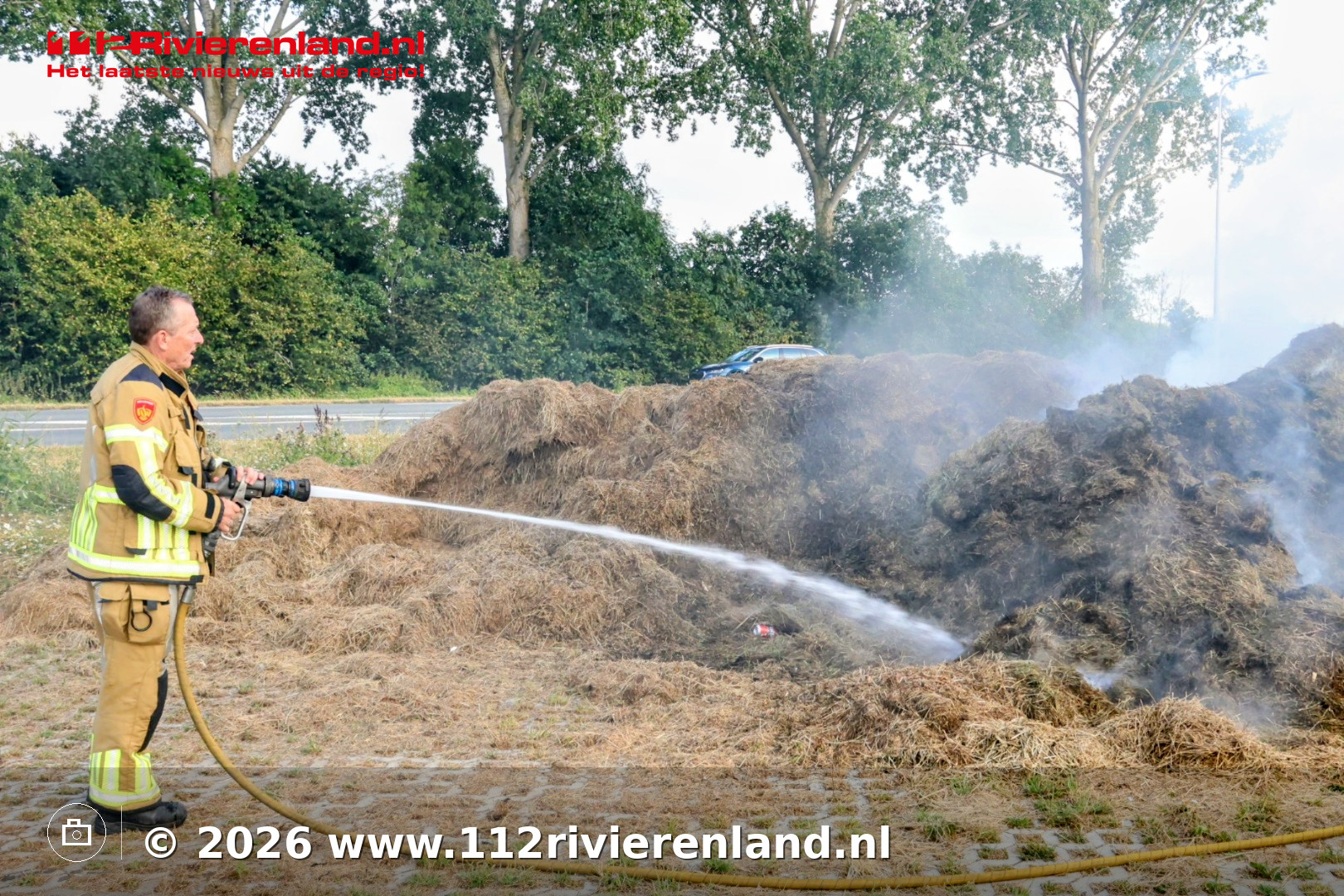 Brandweer blust brandende hooistapel